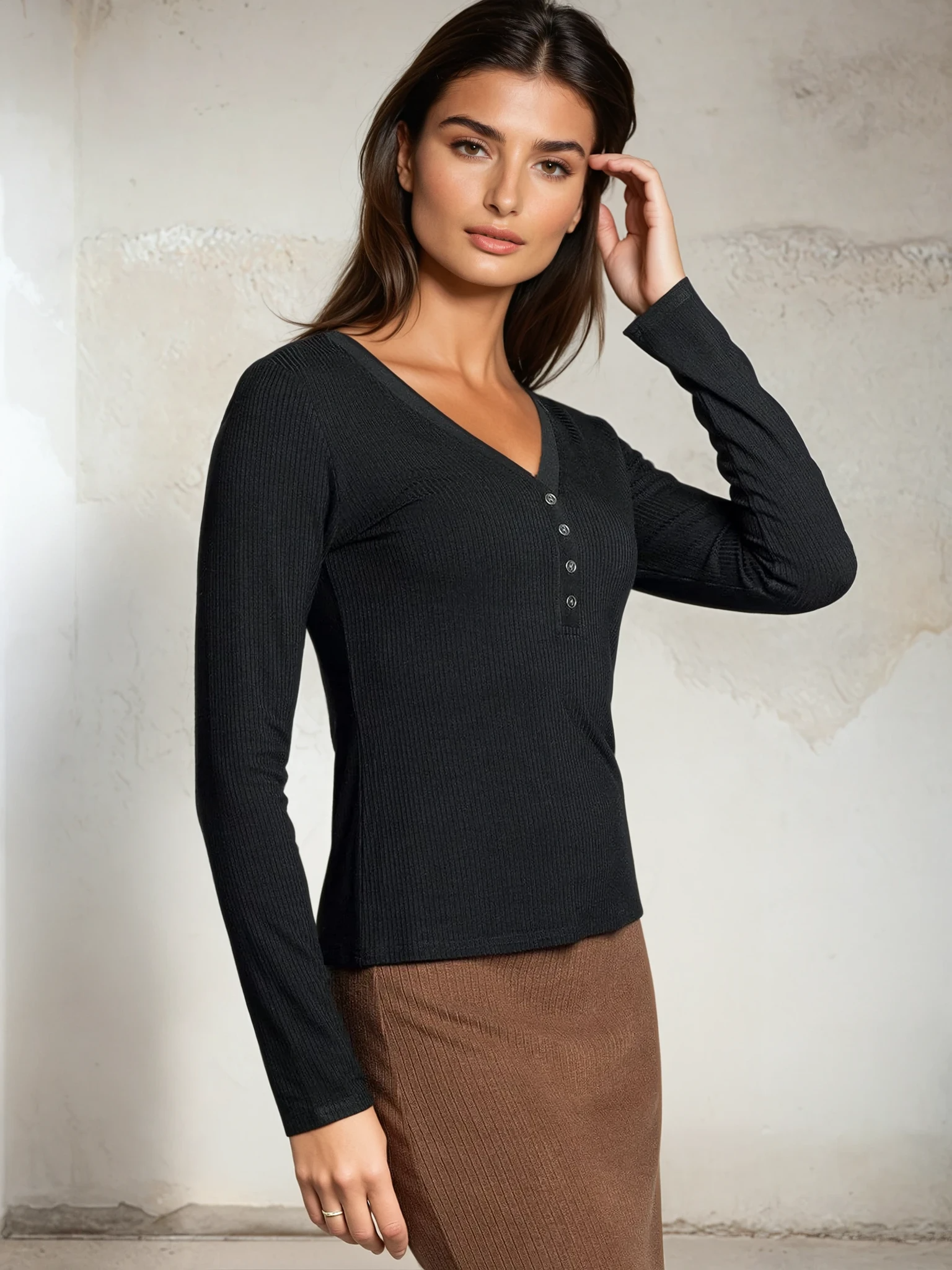 Woman wearing a black long-sleeve top and brown skirt against a neutral background