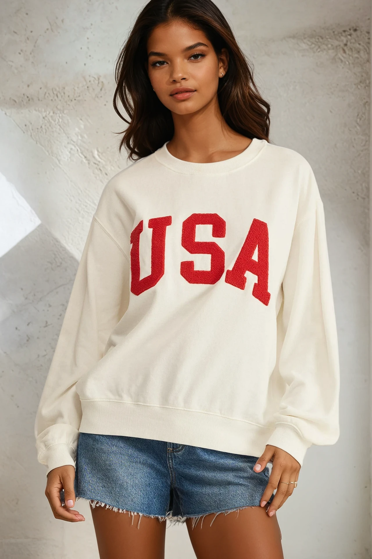 Woman wearing a white sweatshirt with 'USA' in red text against a neutral background