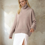Woman wearing a light pink sweater against a textured wall.