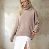 Woman wearing a light pink sweater against a textured wall.