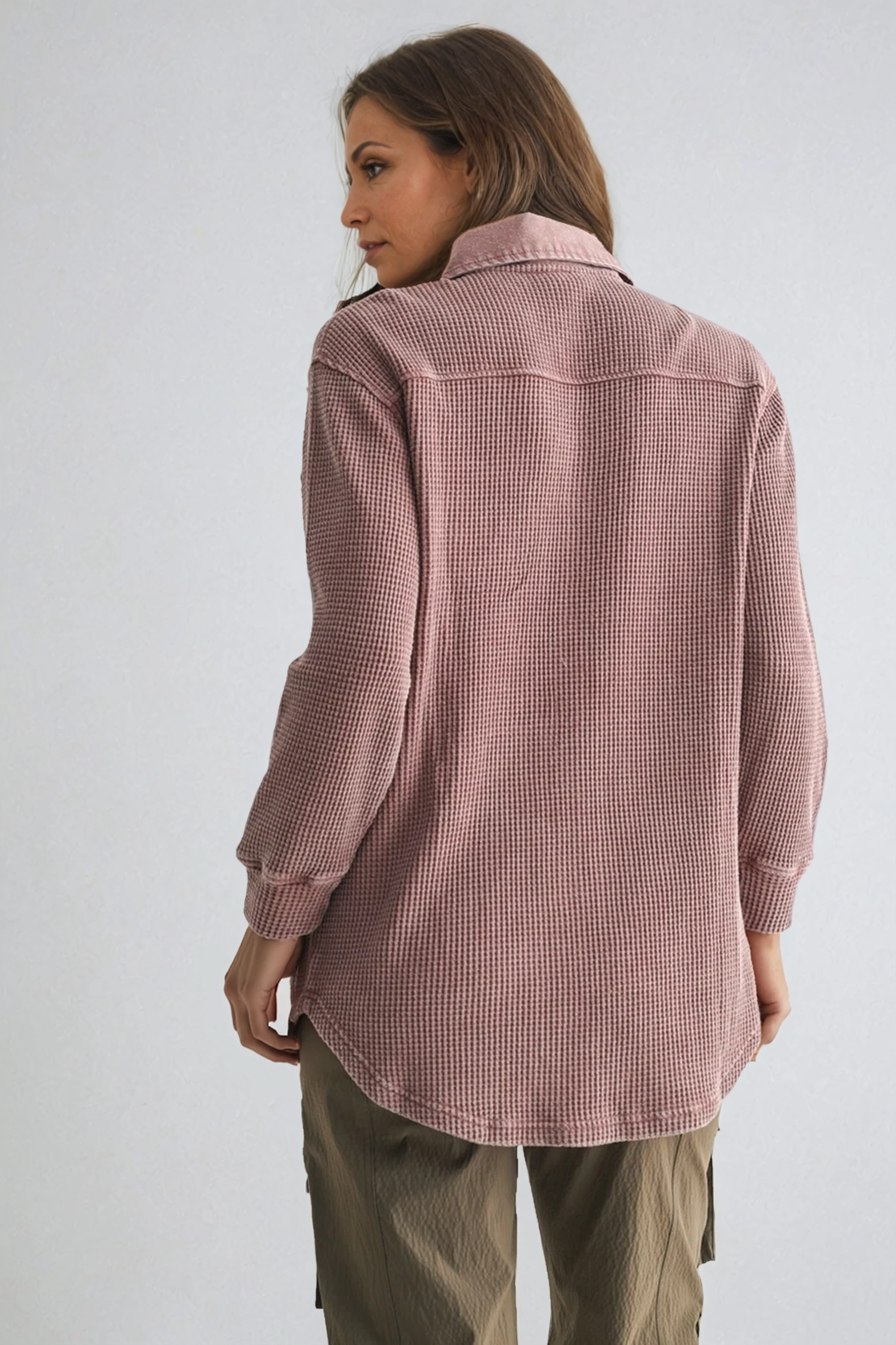 Person wearing a pink textured shirt against a white background