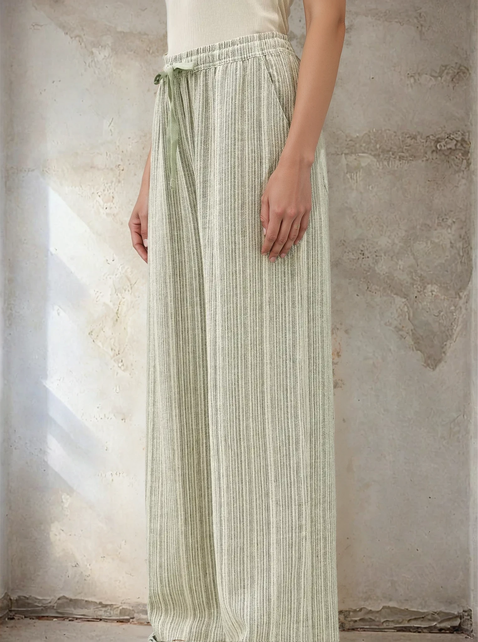 Person wearing a light green striped skirt against a textured wall.