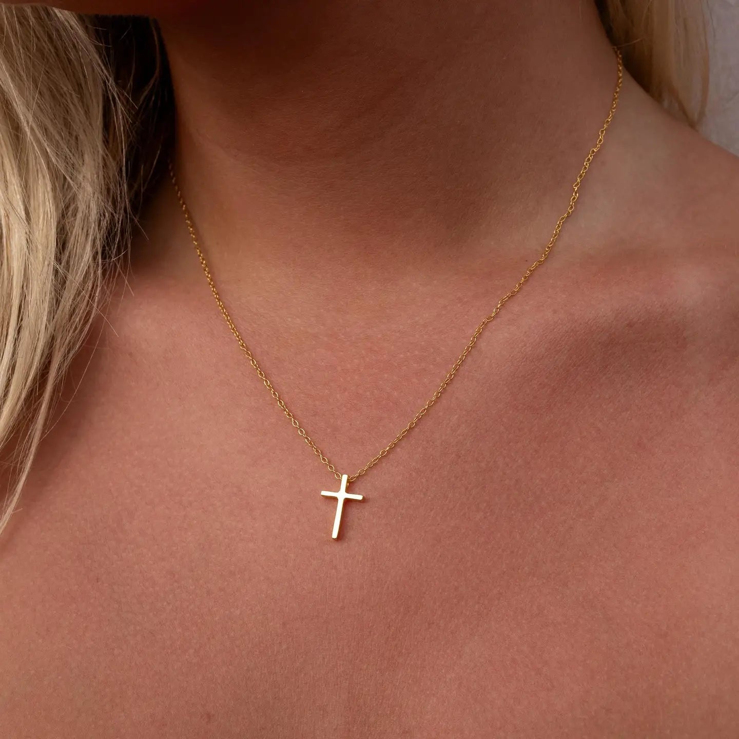 Gold ALCO cross necklace, a jewelry accessory with a sleek gold pendant on a delicate chain.