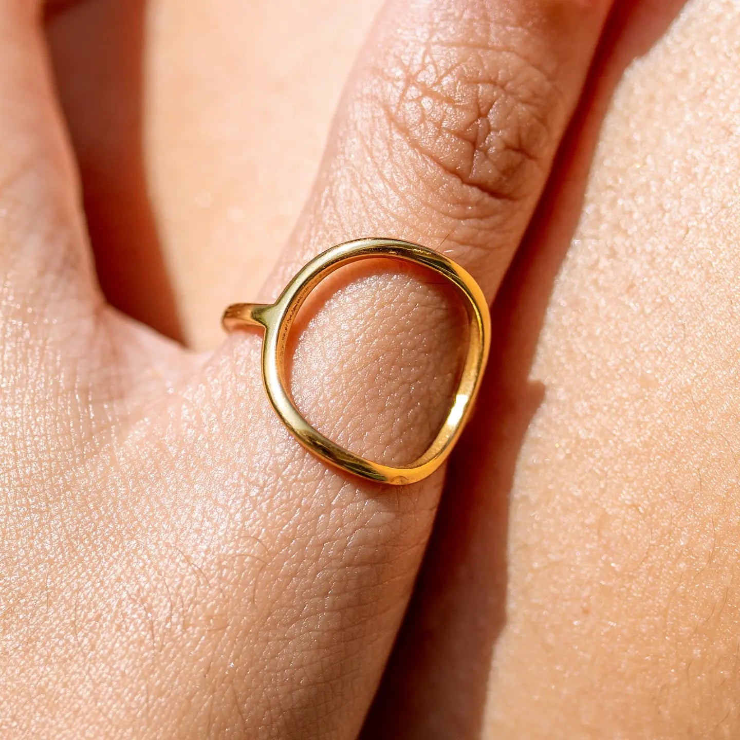 Gold ring on a person's finger with a close-up view of the skin.
