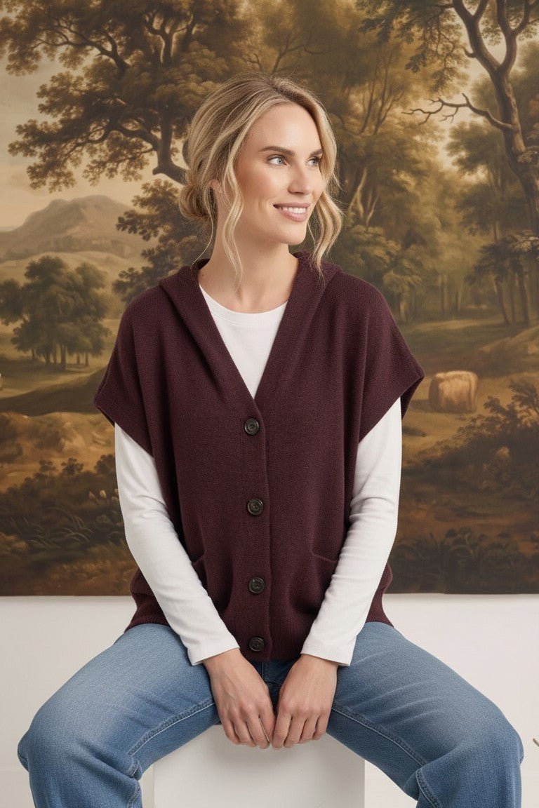 graced burgundy button down hoodie vest worn by a smiling woman over a white long sleeve shirt and blue jeans