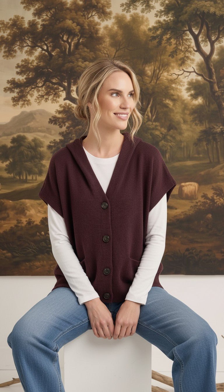 graced burgundy button down hoodie vest worn by a smiling woman over a white long sleeve shirt and blue jeans