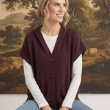 graced burgundy button down hoodie vest worn by a smiling woman over a white long sleeve shirt and blue jeans