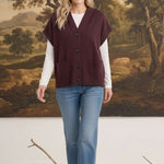 graced burgundy button down sleeveless hoodie layered over a white long sleeve top and blue jeans