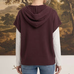Back view of a woman wearing a graced burgundy button down hoodie top over a white long sleeve shirt and blue jeans