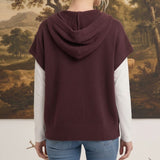 Back view of a woman wearing a graced burgundy button down hoodie top over a white long sleeve shirt and blue jeans