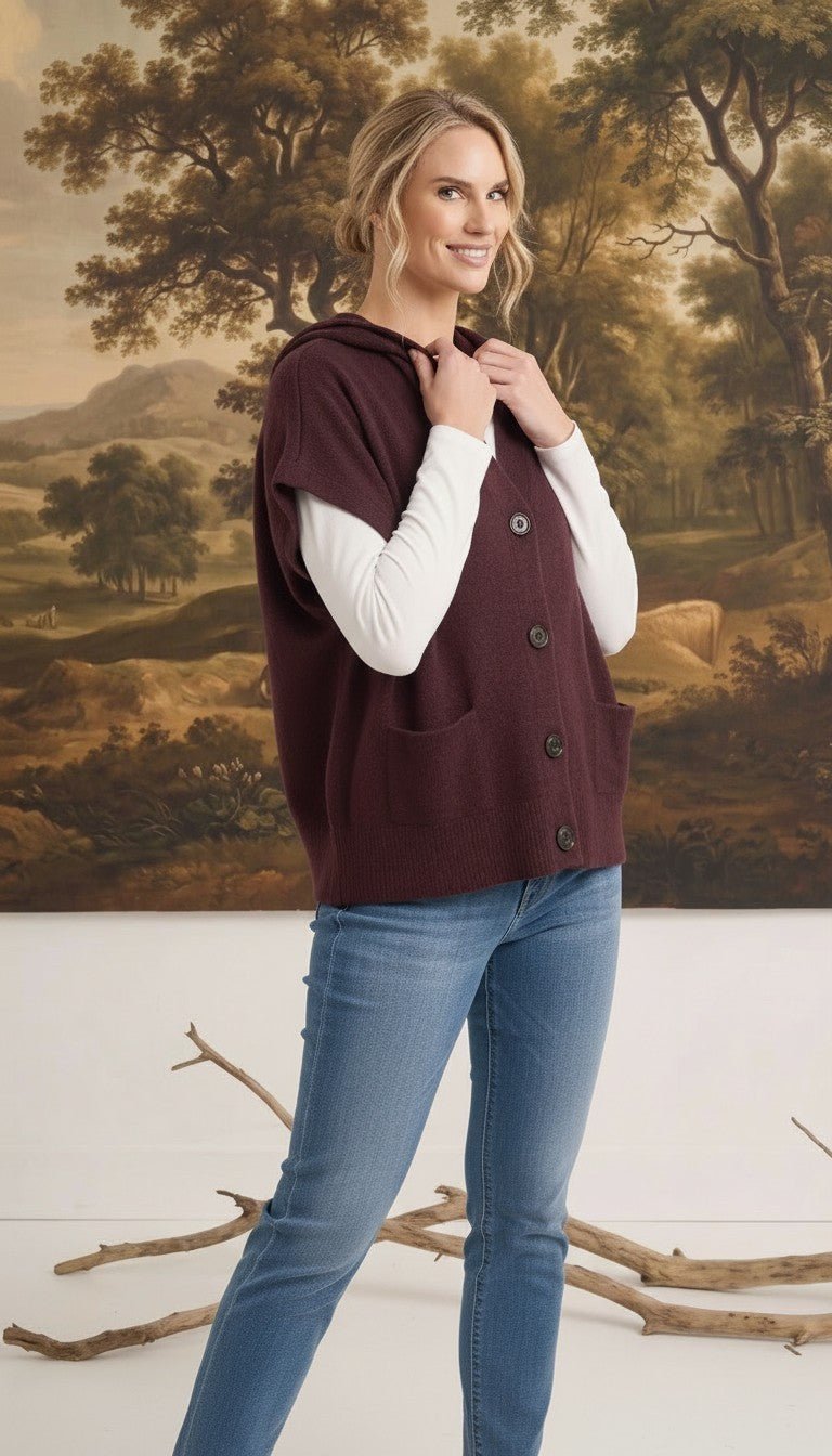 graced burgundy button down sleeveless hoodie with front pockets worn by a woman over a white long sleeve top