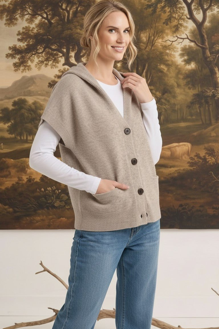 graced taupe button-down hooded vest worn by a woman over a white long-sleeve shirt and blue jeans