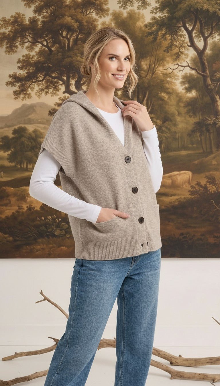 graced taupe button-down hooded vest worn by a woman over a white long-sleeve shirt and blue jeans