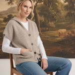 graced taupe button down hooded vest worn over a white long sleeve shirt and blue jeans by a woman on a wooden chair