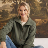 A woman wearing a graced olive mock neck button-down cardigan with a relaxed fit, styled with blue denim jeans.