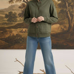 Model wearing a graced olive mock neck button-down cardigan with front pockets, styled with blue jeans and heels.