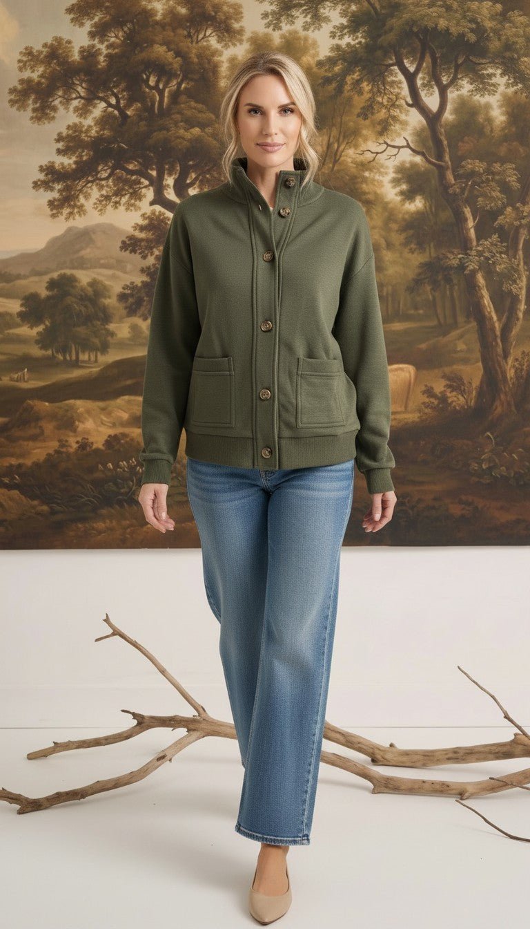 A woman wearing a graced olive green mock neck button-down cardigan with front pockets, paired with blue jeans.