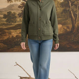 A woman wearing a graced olive green mock neck button-down cardigan with front pockets, paired with blue jeans.