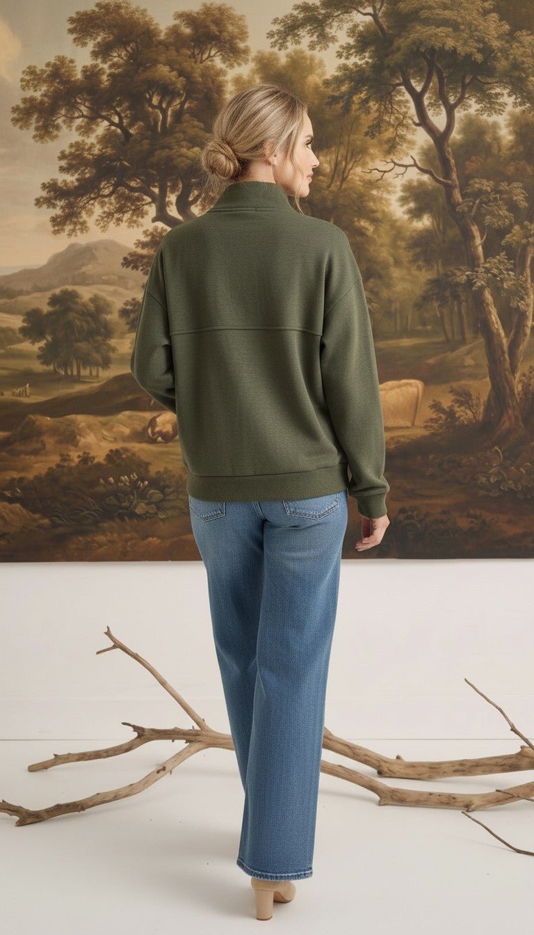 Woman wearing a graced olive mock neck cardigan with a relaxed fit, paired with blue jeans, back view.