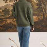 Woman wearing a graced olive mock neck cardigan with a relaxed fit, paired with blue jeans, back view.