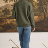 Woman wearing a graced olive mock neck cardigan with a relaxed fit, paired with blue jeans, back view.