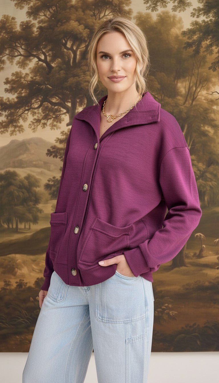 A model wearing a wine-colored graced button-down mock neck cardigan with front pockets and light wash jeans.