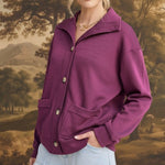 A model wearing a wine-colored graced button-down mock neck cardigan with front pockets and light wash jeans.
