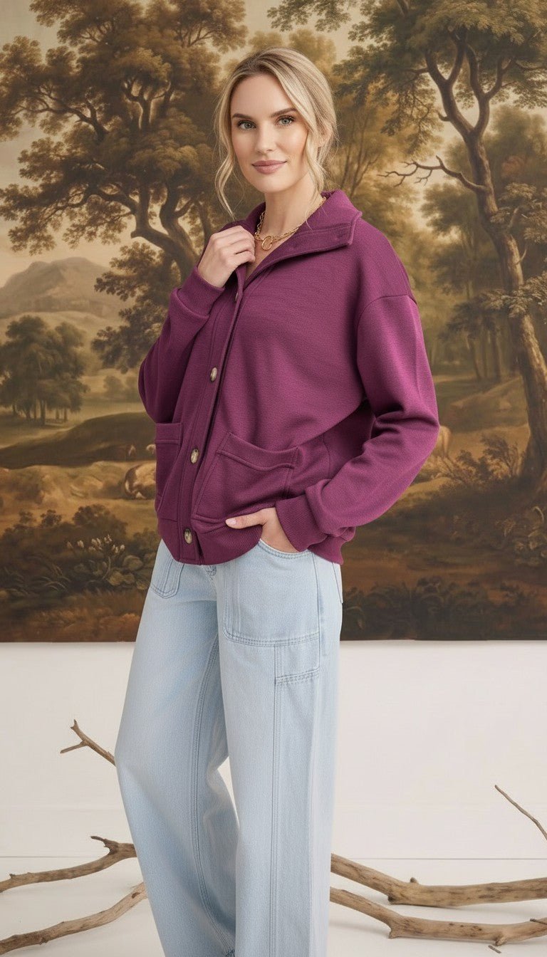 Model wearing a wine-coloured graced button-down mock neck cardigan with front pockets and light wash jeans