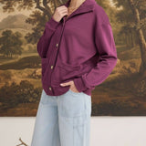 Model wearing a wine-coloured graced button-down mock neck cardigan with front pockets and light wash jeans
