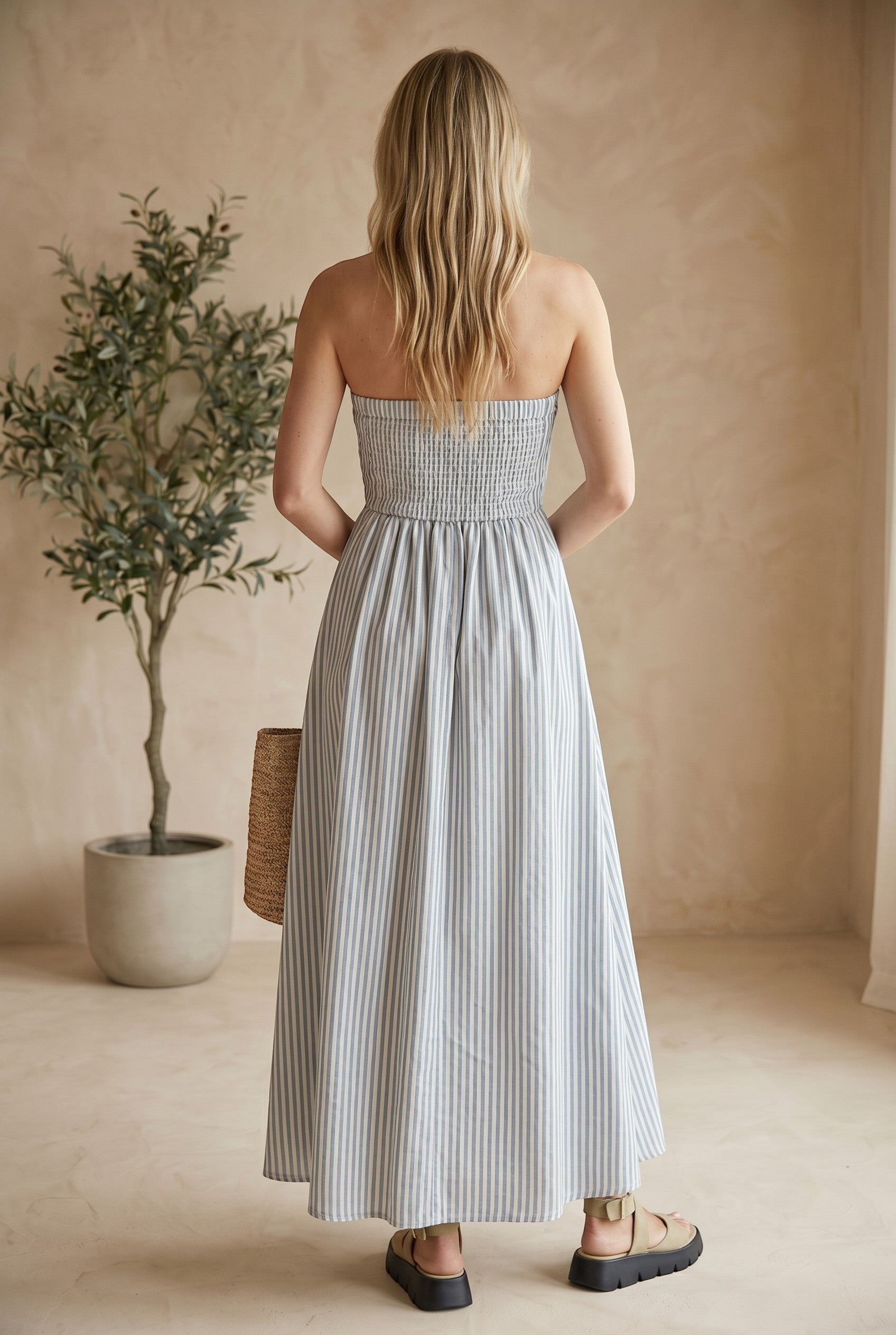 Blue and white striped strapless maxi dress with a smocked bodice by By Together, featuring a flowing silhouette and vibrant pattern.