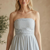 Blue and white striped strapless maxi dress by By Together with a smocked bodice, flowing skirt, and relaxed summer style.
