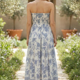 Blue and white floral smocked strapless midi dress by By Together, featuring a fitted bodice and flowing cotton-rayon fabric.