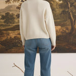 graced cream crew neck cardigan worn by a woman with blonde hair in a bun, paired with blue jeans, back view