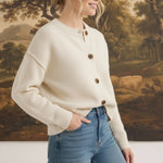 graced cream crew neck cardigan with button front, worn by a woman with blonde hair in a bun with blue jeans