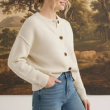 graced cream crew neck cardigan with button front, worn by a woman with blonde hair in a bun with blue jeans