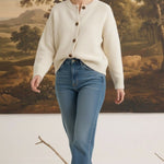 graced cream crew neck cardigan with button front, worn by a blonde model with blue jeans in a studio setting