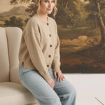 Model wearing a graced mushroom crew neck cardigan with brown buttons, paired with light wash jeans in a studio.