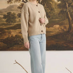 Model wearing a graced mushroom crew neck cardigan with button front and relaxed fit paired with light wash jeans
