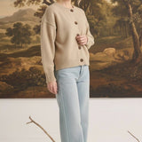 Model wearing a graced mushroom crew neck cardigan with button front and relaxed fit paired with light wash jeans