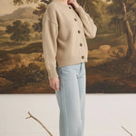 Model wearing a graced mushroom crew neck cardigan with button front and relaxed fit paired with light wash jeans