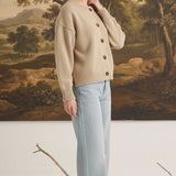 Model wearing a graced mushroom crew neck cardigan with button front and relaxed fit paired with light wash jeans