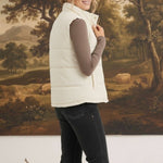 graced cream corduroy puffer vest worn by a woman over a brown long-sleeve top and black jeans
