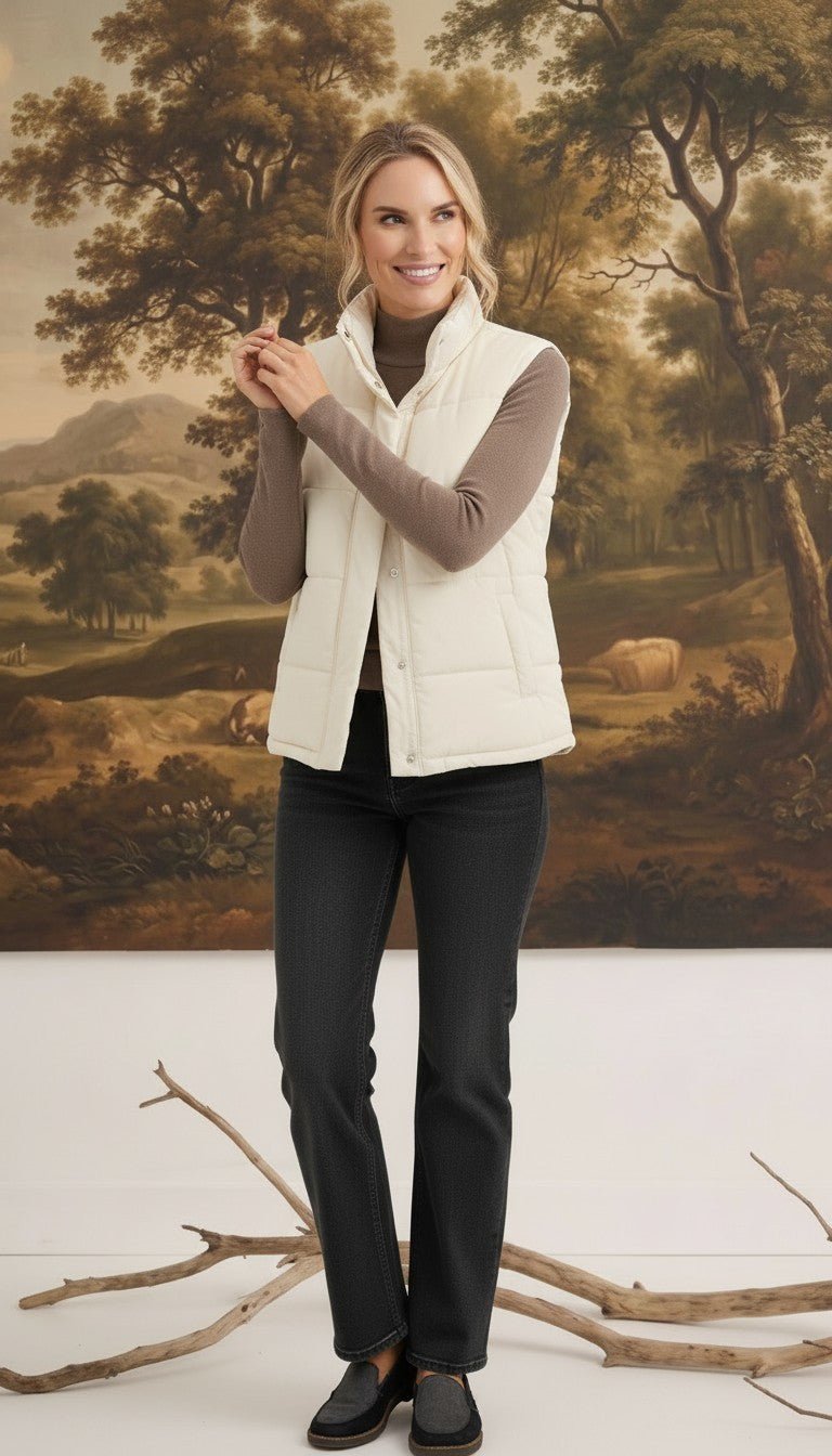 Woman wearing a cream corduroy puffer vest by graced over a brown long-sleeve top and black jeans