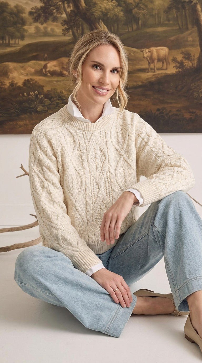 graced cream cable knit crew neck sweater worn by a woman with a white collared shirt and light wash jeans