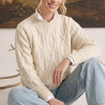 graced cream cable knit crew neck sweater worn by a woman with a white collared shirt and light wash jeans