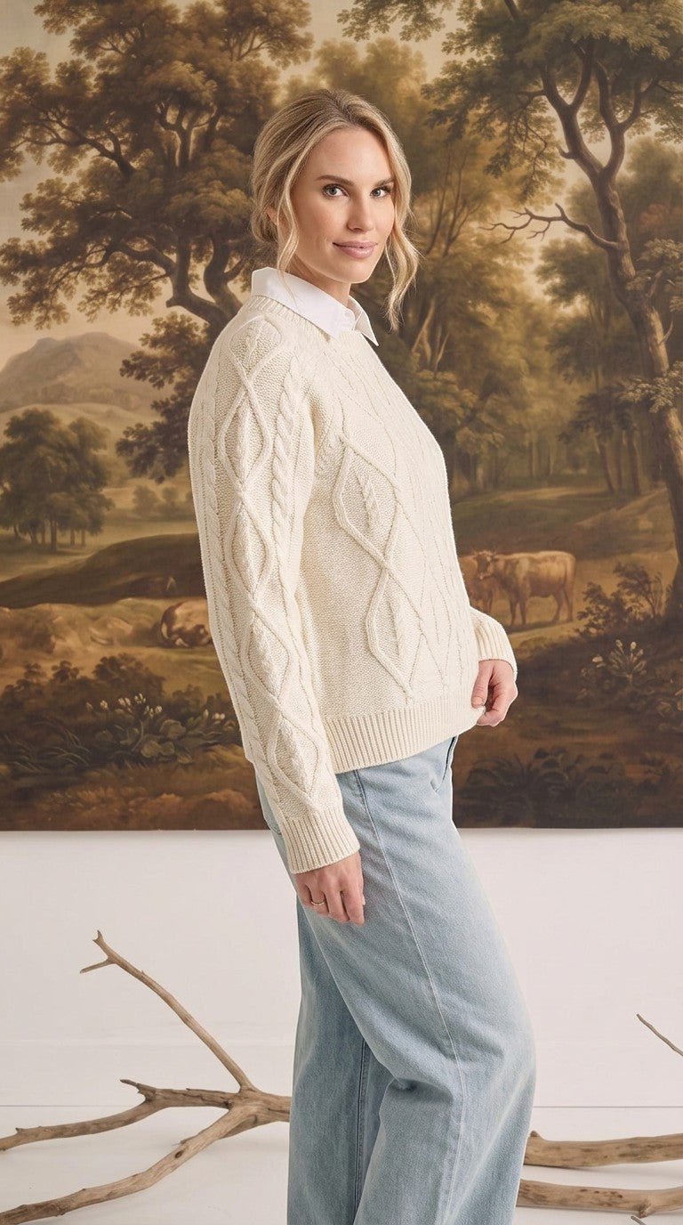 graced cream cable knit crew neck sweater worn by a woman with a white collared shirt and light blue jeans