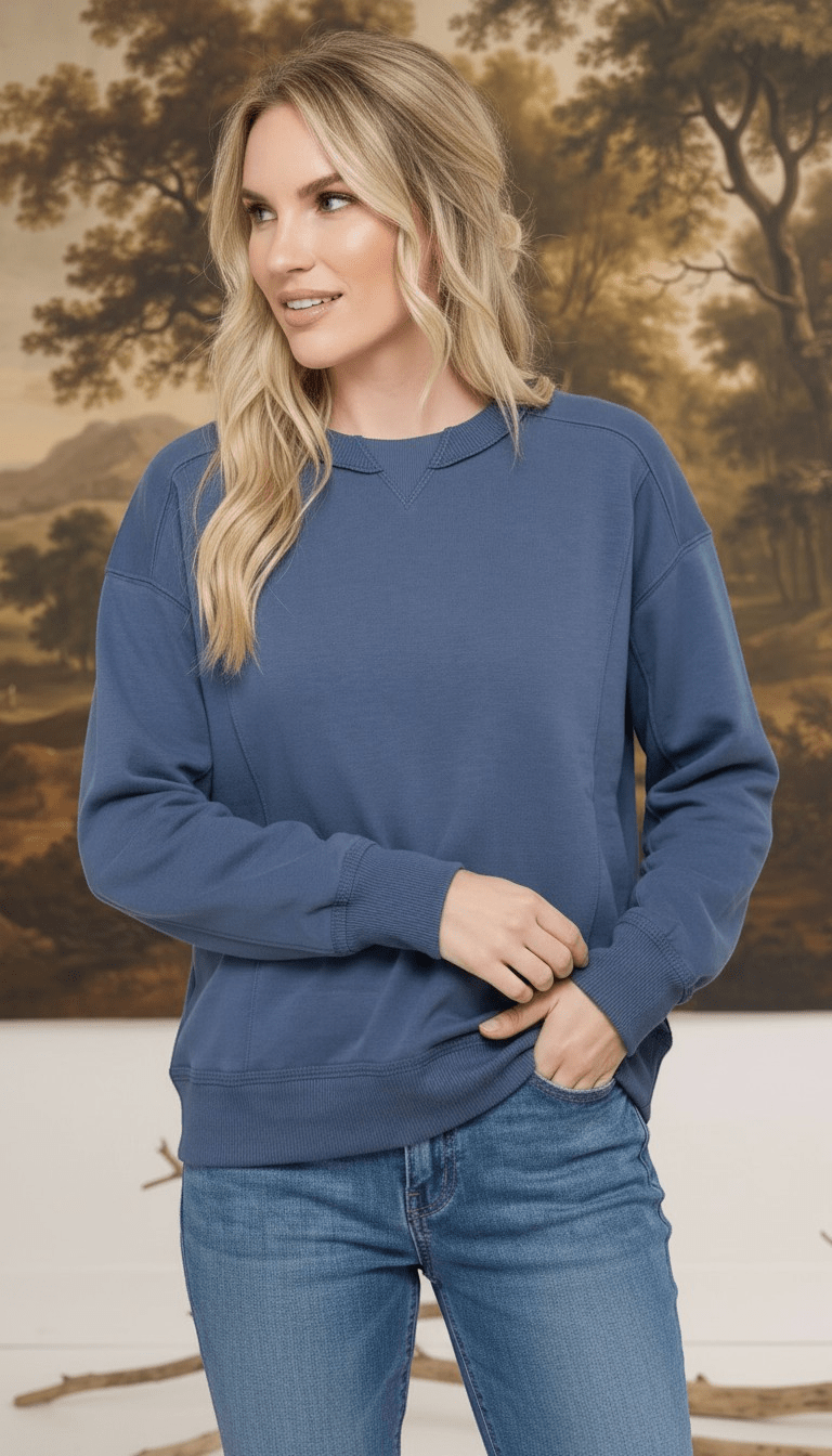 A woman wearing a graced indigo crewneck pullover top with ribbed cuffs and a classic neckline, styled with jeans.
