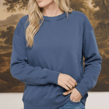 A woman wearing a graced indigo crewneck pullover top with ribbed cuffs and a classic neckline, styled with jeans.