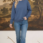 Woman wearing a graced indigo blue crewneck pullover with ribbed cuffs and hem, styled with blue jeans.
