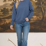 Woman wearing a graced indigo blue crewneck pullover with ribbed cuffs and hem, styled with blue jeans.